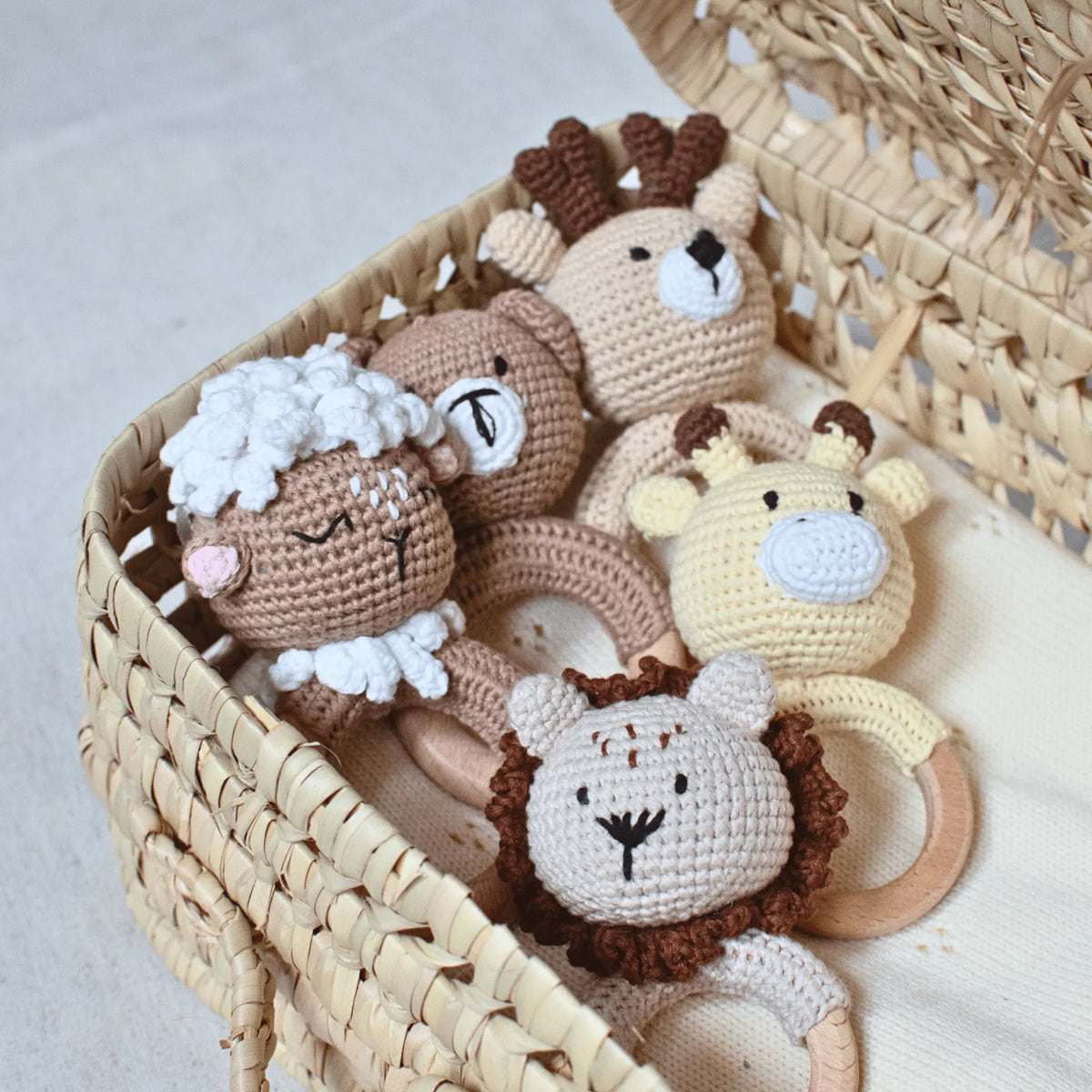 ensemble de hochets dans un panier, il y a un ourson, un agneau, un cerf, une girafe et un lion