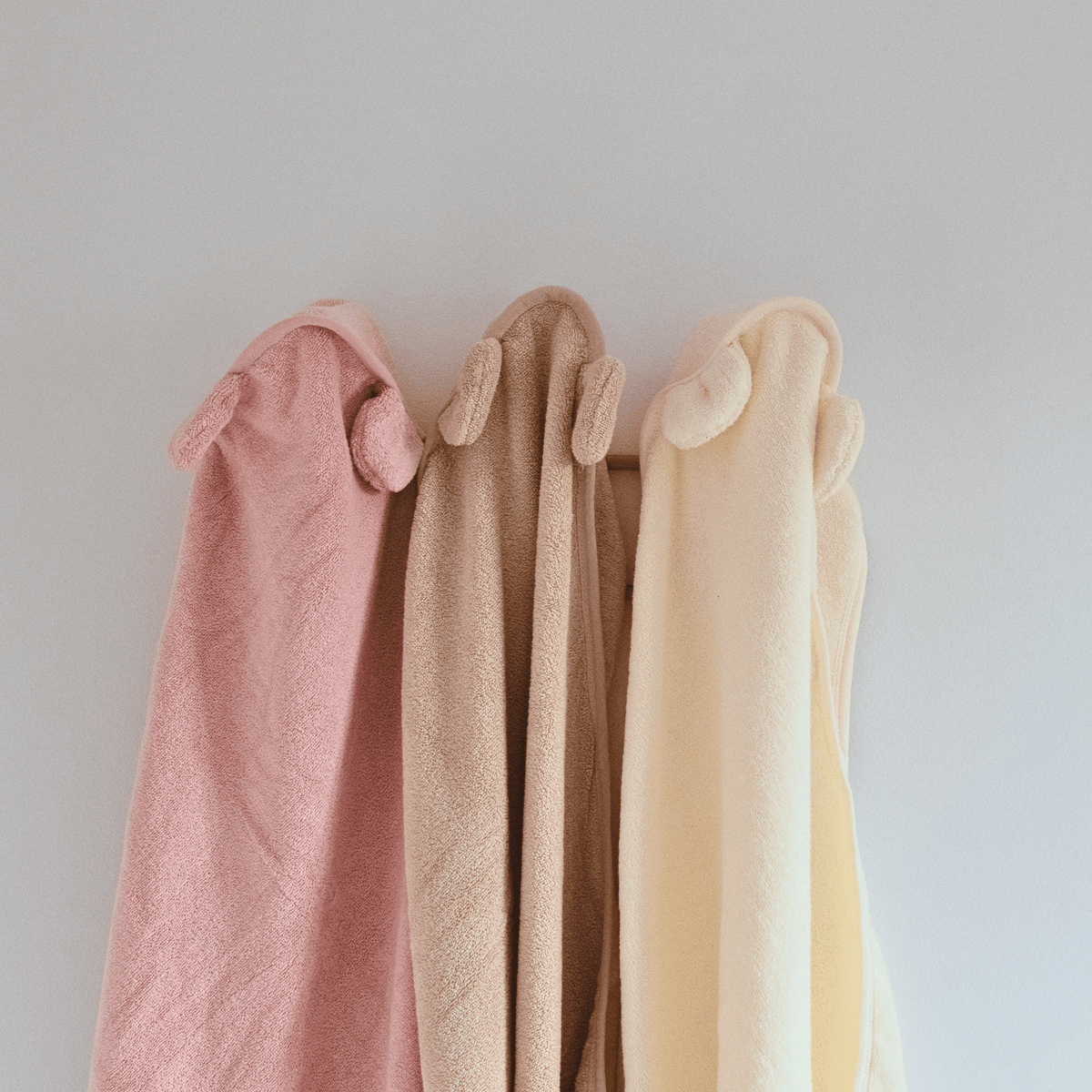 capes de bain personnalisé avec différents prénoms accroché au mur