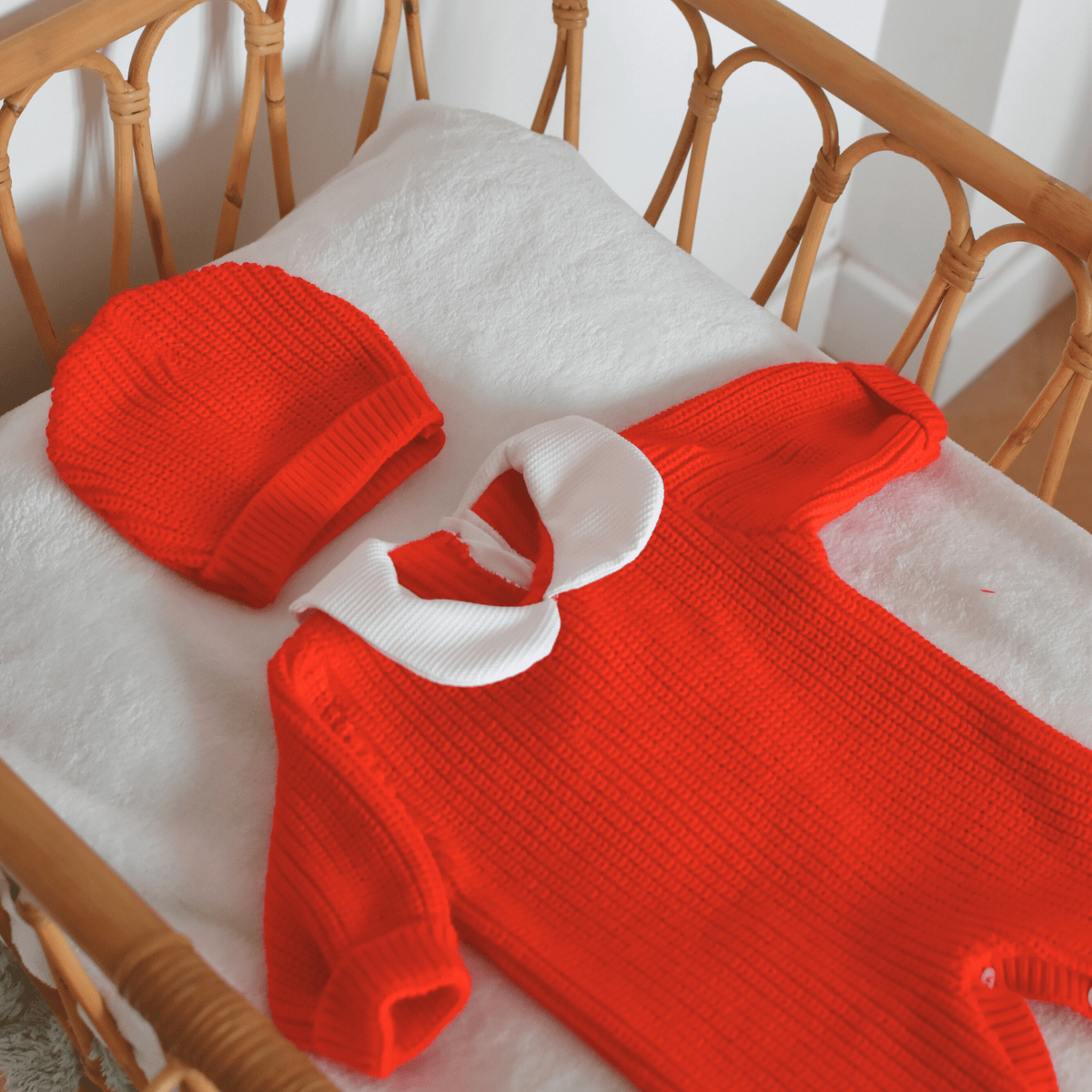 Ensemble naissance rouge en tricot coton avec bonnet dans un berceau